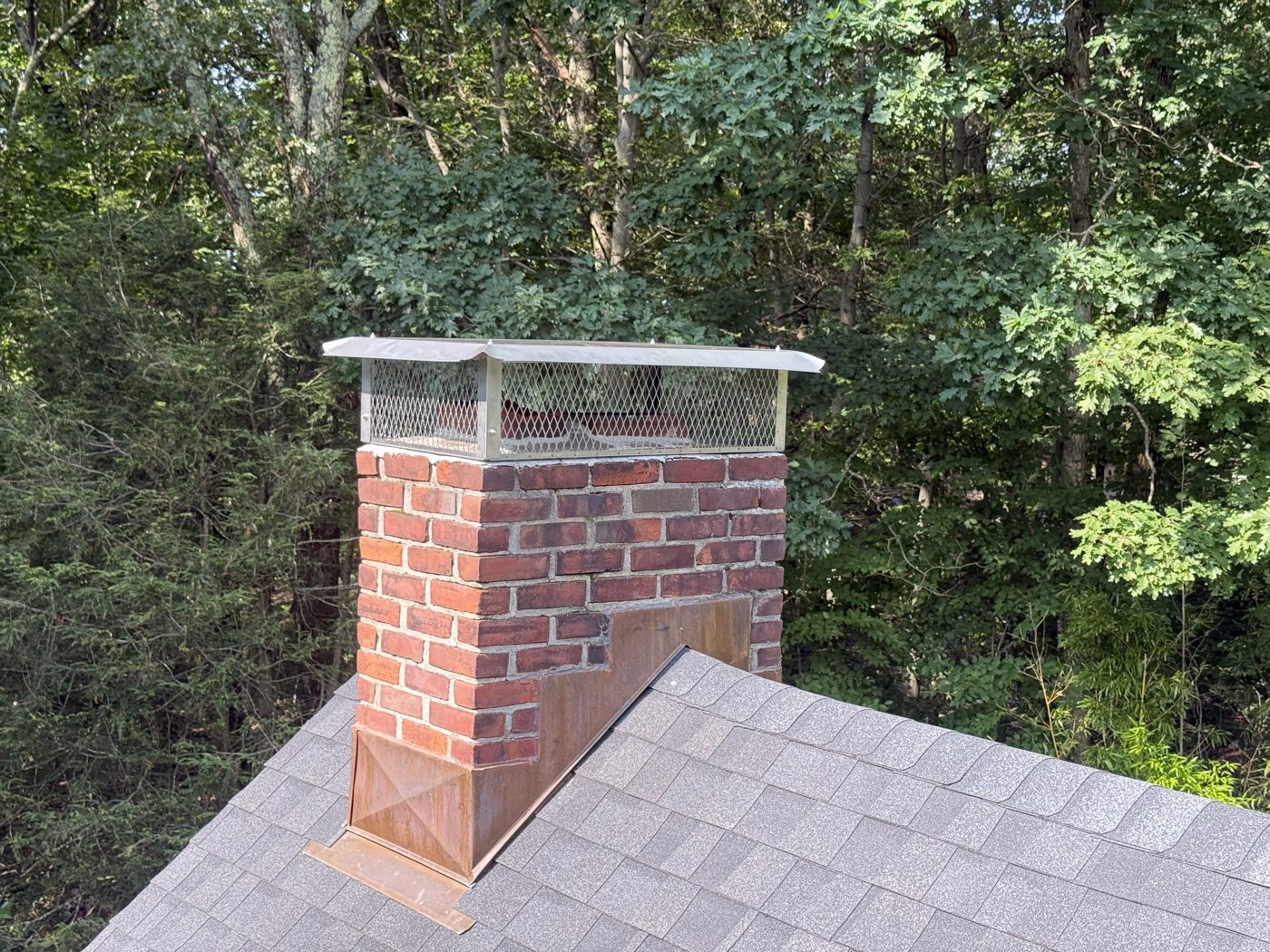 Chimney cap and copper flashing on a shingle roof